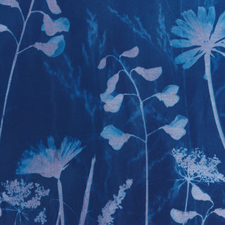 A close-up of a blue floral pattern cyanotype print with light blue and pale lavender botanical silhouettes on a deep blue background.